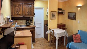 A compact kitchen with wooden cabinets, a dining table, and a sofa.