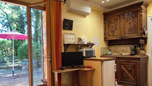 A compact kitchen with wooden cabinets, a microwave, a small refrigerator, and a dining area with a table and chairs.