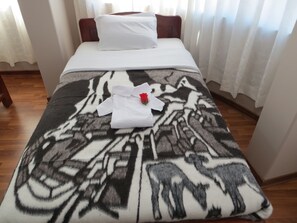 A neatly made bed with a patterned blanket, white pillows, and a red rose. - La Casa De Yoni (Puno)