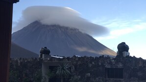 Un paysage volcanique avec une grande montagne, un mur de pierre et deux structures en forme de dôme.