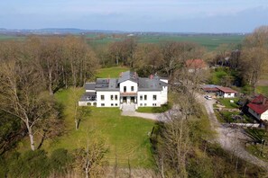 Une grande maison à deux étages, dotée d’un vaste jardin à l’avant et d’une allée menant à l’entrée.
