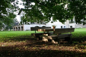 Una mesa de picnic con bancos en un parque, con un edificio al fondo.