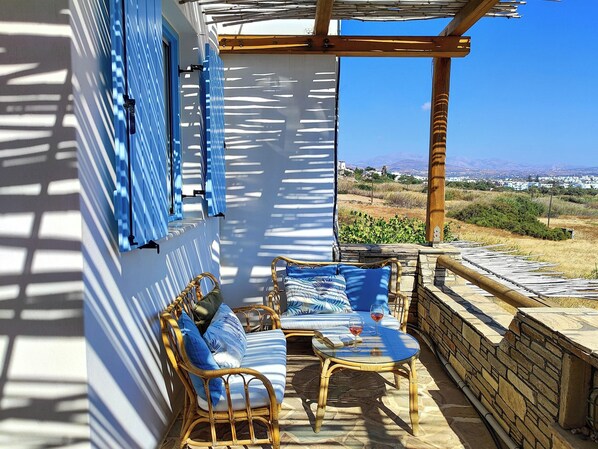 Une pièce avec vue sur le paysage, meublée de mobilier en osier et dotée d’un mur en pierre.