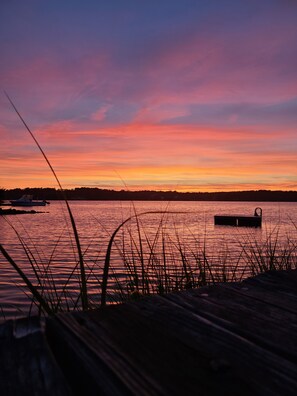 A sunset over a calm body of water with boats and a dock. - Beautiful Waterfront Home with Beach, Dock, Deck, & Great Views! capeoceanvista (Yarmouth)