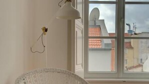 A wicker chair with a white cushion in a room with a large window. - Tracey & Neill's Place by Portugal Portfolio (Misericórdia/ Lisbon)