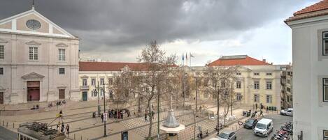 Ein Stadtplatz mit Straßenbahn, Gebäuden und einem Brunnen.
