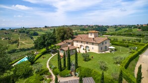 A large, two-story house with a tiled roof, surrounded by well-maintained gardens and a swimming pool. - Luxury Villa located between Florence and Siena. A/C, swimming pool and SPA! (Tavarnelle val di Pesa)