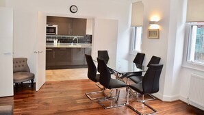 A modern kitchen with dark cabinets, a glass-top table, and black chairs.