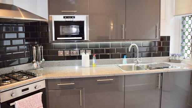A modern kitchen with a gas stove, microwave, stainless steel sink, and dark cabinetry.