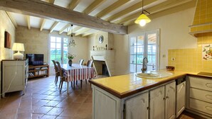 A spacious kitchen with a large island, wooden beams, and a dining area with a table and chairs. - Renovated Stone House with Garden in the Heart of the Saint-Émilion Vineyards (ST EMILION)