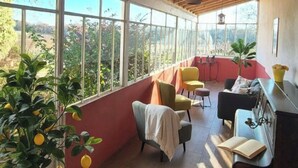 A sunlit room with a view of greenery outside, a piano, and a table with a book. - Renovated Stone House with Garden in the Heart of the Saint-Émilion Vineyards (ST EMILION)