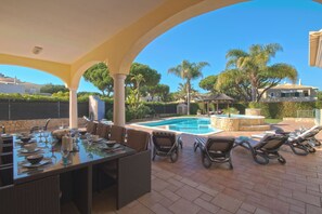 Un espace extérieur aménagé pour les repas, avec une piscine, des chaises longues et une pergola.