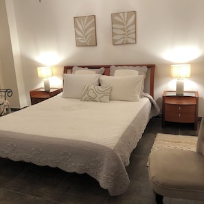 A neatly made bed with a quilted cover, two bedside lamps, a wooden headboard, and a small bedside table with a lamp. - Incredible rental Porto-Vecchio South Corsica close to the sea and village  (Porto-Vecchio)