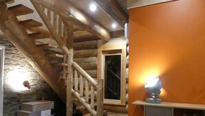 A rustic wooden staircase in a room with a stone wall and a wooden cabinet. - ----The evening Star---- (Saint-Martin-de-la-Porte)