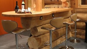 A rustic wooden interior with a bar area featuring a wooden log backdrop, a round bar counter, and four bar stools with metallic bases. - ----The evening Star---- (Saint-Martin-de-la-Porte)