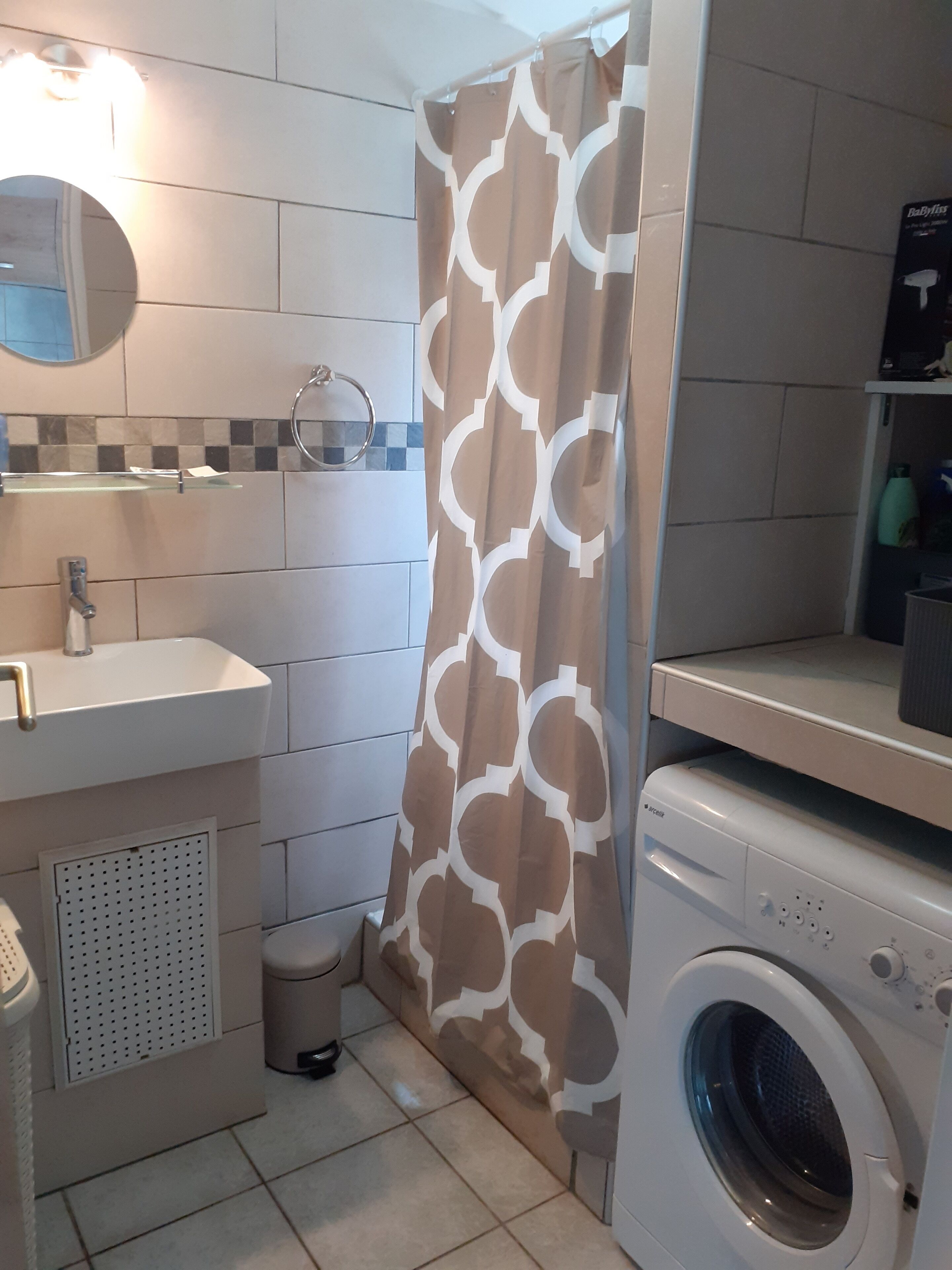 Une salle de bain équipée d’un lavabo, d’un miroir, de toilettes et d’un lave-linge.
