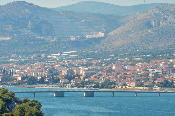 A coastal cityscape with a bridge spanning a river, surrounded by hills and residential buildings.