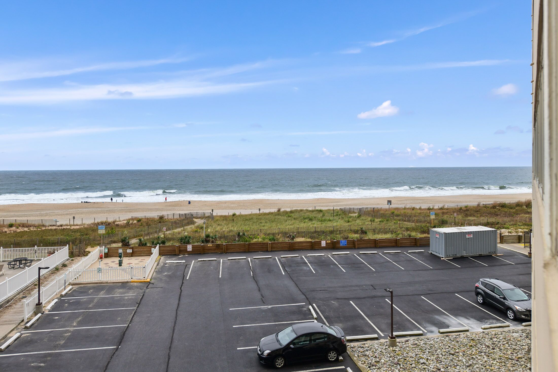 A parking lot with a view of the beach and ocean.