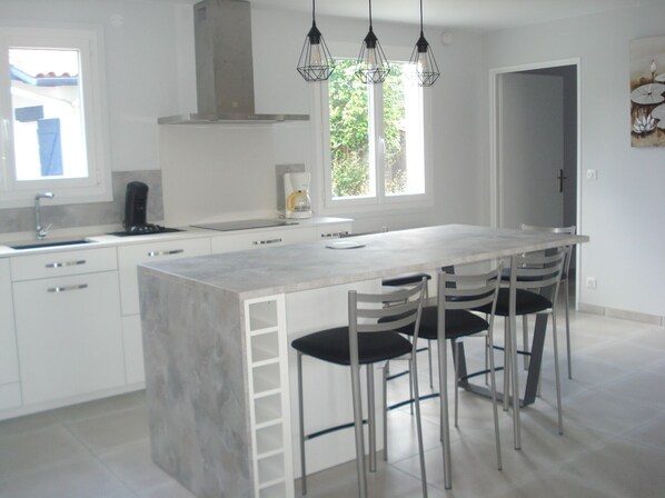 A modern kitchen with a central island, stainless steel appliances, and pendant lighting.