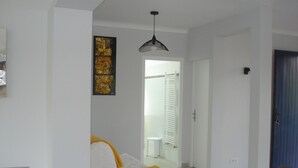 Ett modernt vardagsrum med en vit soffa, ett matbord och en stor, abstrakt tavla på väggen.