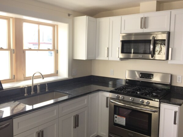 A kitchen with white cabinets, a stainless steel stove, and a microwave.