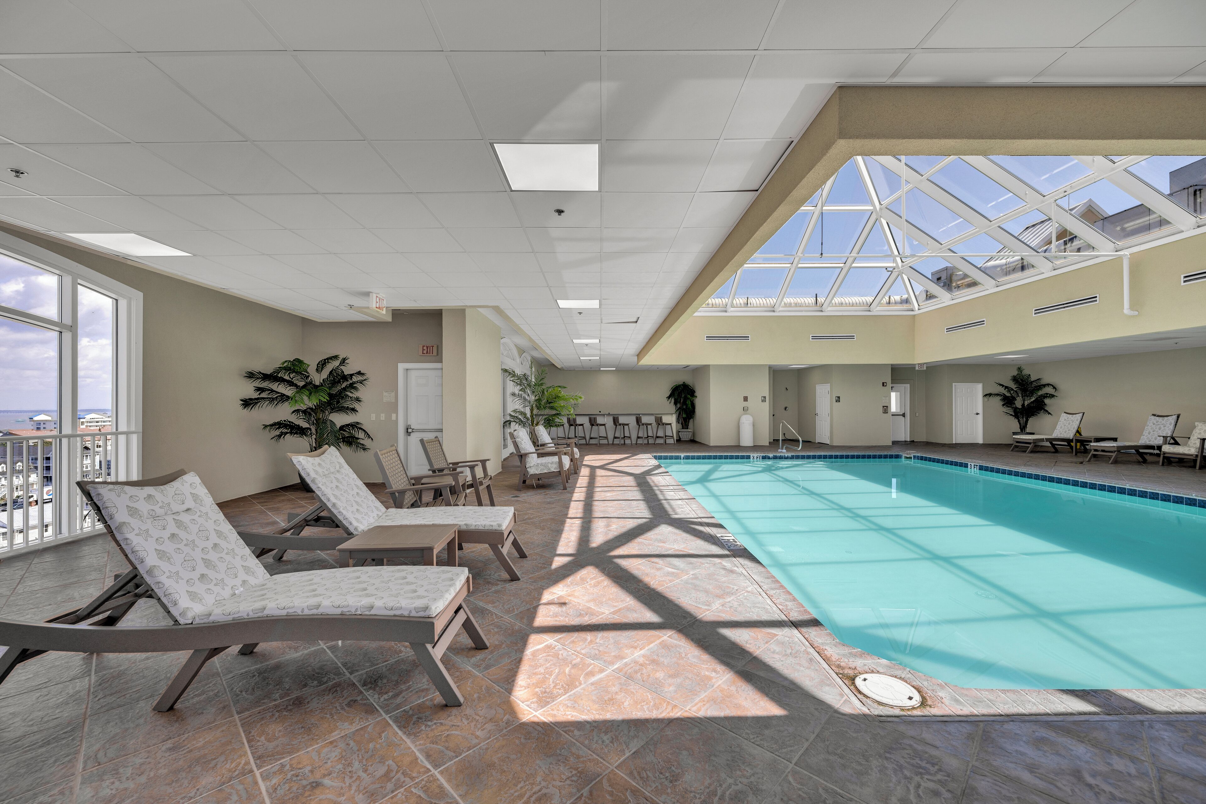 An indoor swimming pool with lounge chairs and a skylight.