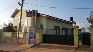 A two-story building with a sign for 'Huford Lodge' advertising rooms and a website. - Huford  Lodge (Oyibi)
