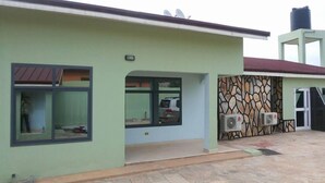 A building with a green facade, large windows, and a stone-patterned wall. - Huford  Lodge (Oyibi)
