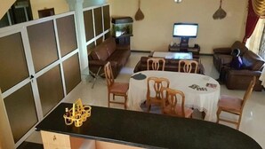 A dining area with a round table, chairs, and a black countertop. - Huford  Lodge (Oyibi)