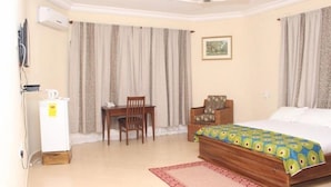 A hotel room with a bed, a desk, a chair, and a small table. - Huford  Lodge (Oyibi)