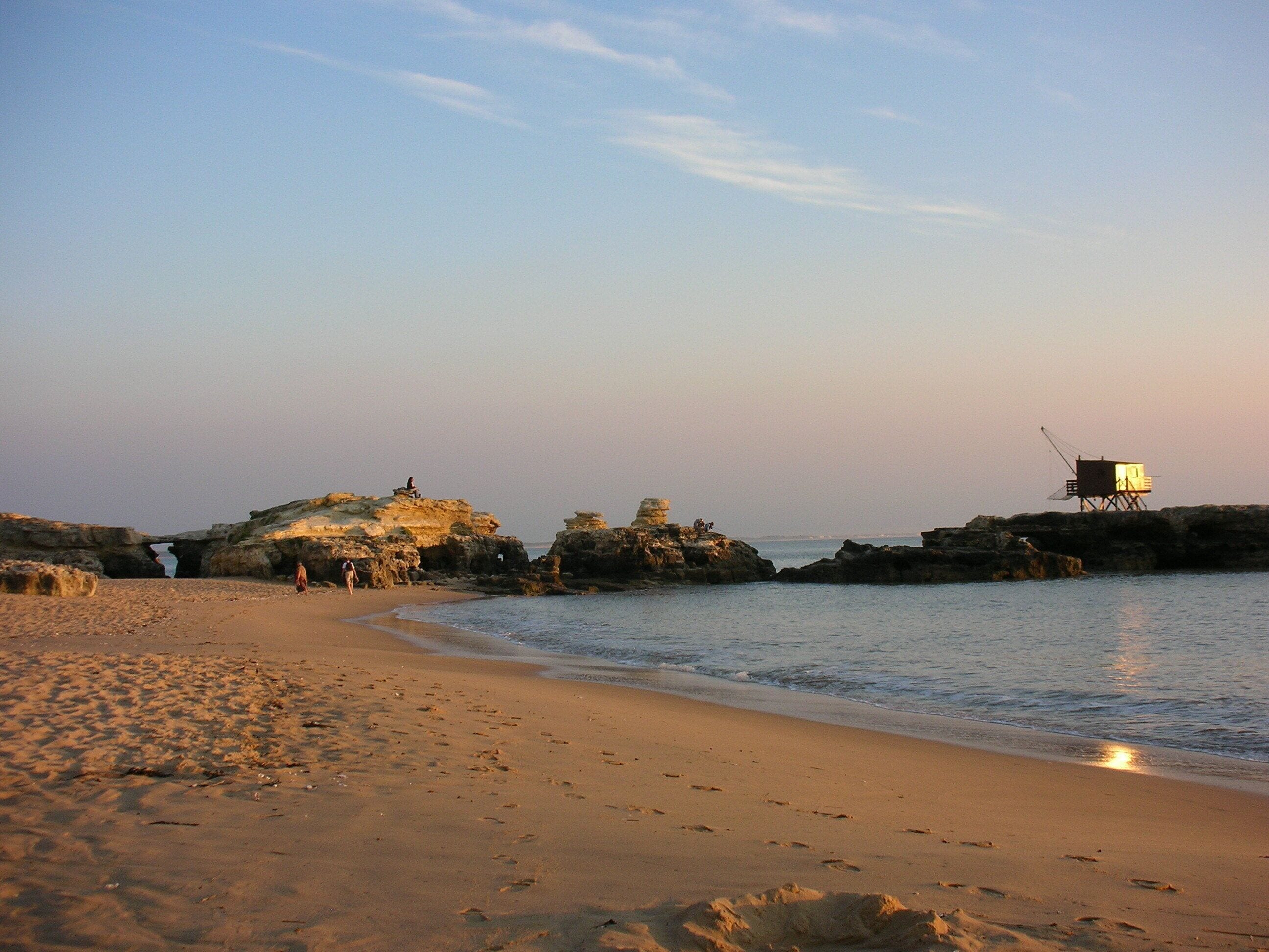 A beach with rocky formations and a wooden structure on stilts.