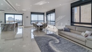 A spacious living area with a large dining table, a sofa, and a view of the city through large windows. - Jerusalem Penthouse (Jerusalem)