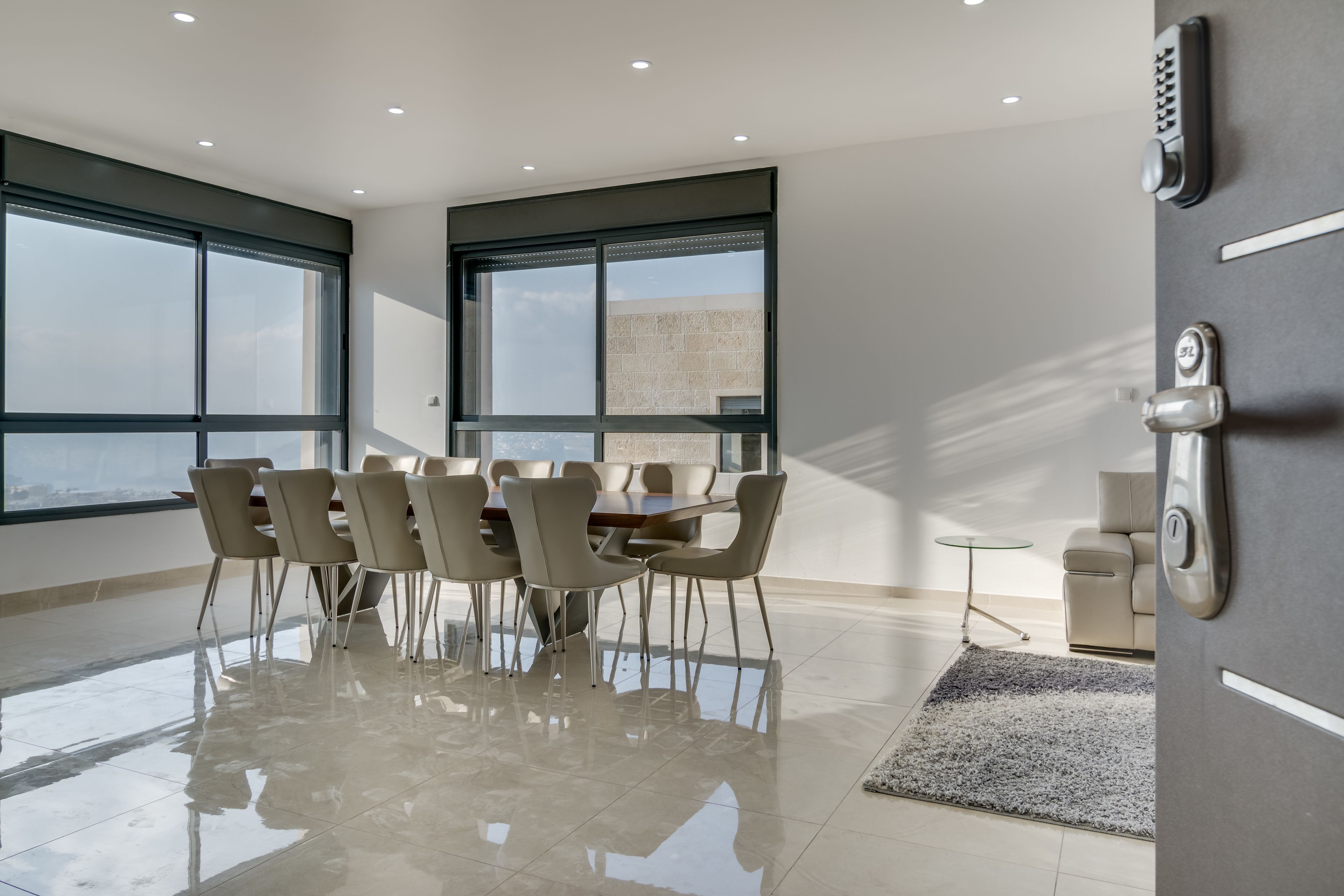 A modern dining area with a large table and chairs, large windows, and a view of the city.