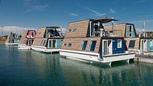 Una fila de casas flotantes con balcones, unidas por pasarelas, amarradas en aguas tranquilas.