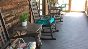 A wooden porch with rocking chairs and a table, a sign reading "On the porch Sometimes I do and sometimes I don't", and a view of the outside. - Fox Creek Cabin in the woods with stream (Narvon)