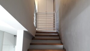 A staircase with wooden steps and white walls, leading to a landing with a metal railing. - DUPLEX LA PUNTILLA (Chacras de Coria)