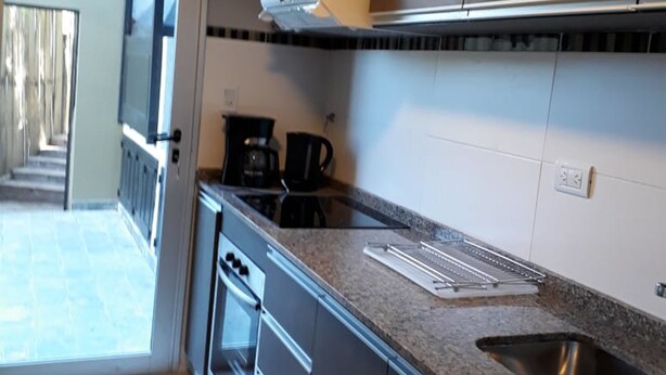 A modern kitchen with a built-in oven, a coffee maker, and a stainless steel sink. - DUPLEX LA PUNTILLA (Chacras de Coria)