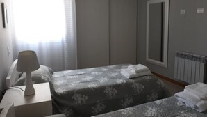A hotel room with a bed, a bedside table with a lamp, a window with curtains, and a radiator. - DUPLEX LA PUNTILLA (Chacras de Coria)