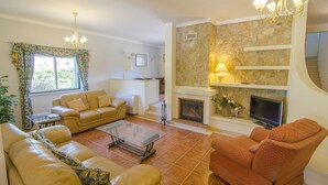 Una sala de estar con chimenea, sofá, sillón y televisor.