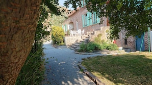 A gravel path leading to a brick house with a porch and outdoor seating. - Les Chambres du Relais (Liettres)