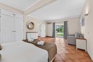 A hotel room with a bed, a desk, a chair, a wardrobe, a mirror, and a view of the outdoors.