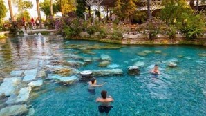 Piscina cristalina con rocas y una persona nadando.