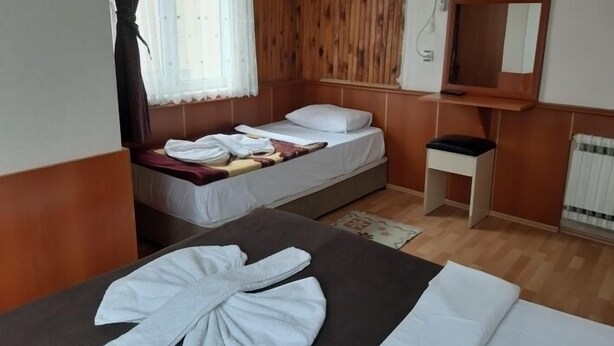 Una habitación con cama, una mesita, un espejo y una ventana con cortinas.