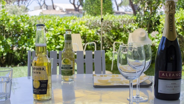 Een tafel met een fles Corona Extra, een fles Somersby appelcider, een fles Tinto Bruto en twee glazen.
