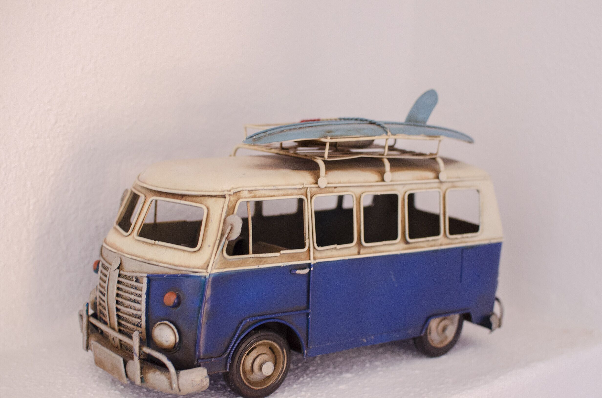 A vintage model van with a surfboard on top.