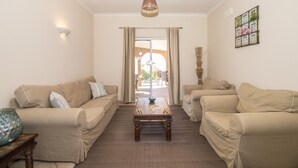 Un salon avec deux canapés beige, une table basse en bois et une grande fenêtre avec des rideaux.