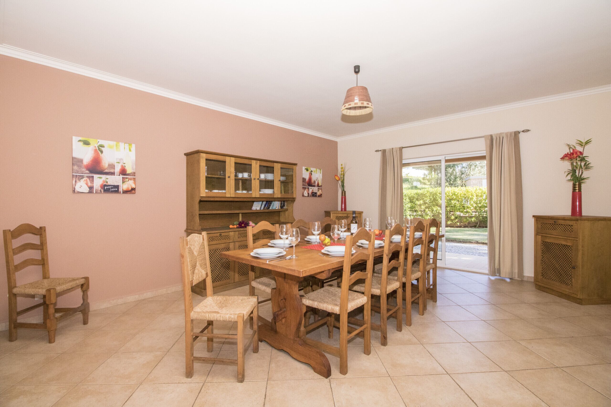 A dining area with a wooden table and chairs, a cabinet, and a view through a glass door.
