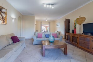 A living room with two sofas, a coffee table, a TV on a wooden cabinet, and a painting on the wall. - Villa Anita | 5 Bedrooms | Private | Vilamoura (Vilamoura)