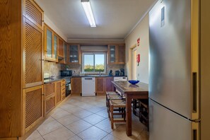 A compact kitchen with wooden cabinets, a built-in dishwasher, and a stainless steel refrigerator. - Villa Anita | 5 Bedrooms | Private | Vilamoura (Vilamoura)