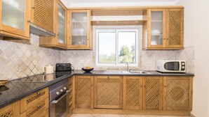 Une cuisine avec des meubles en bois, un four à micro-ondes, une cuisinière et une fenêtre.
